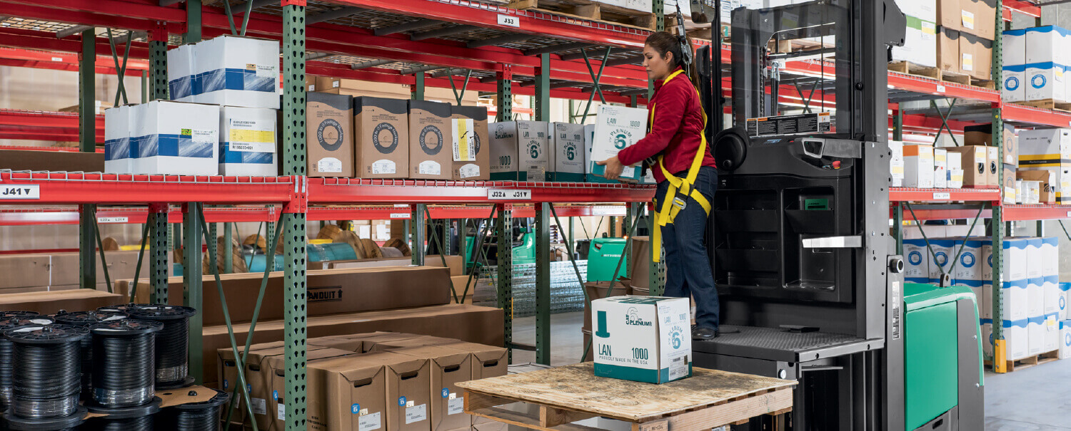 Woman on Mitsubishi order picker lifting box from racking